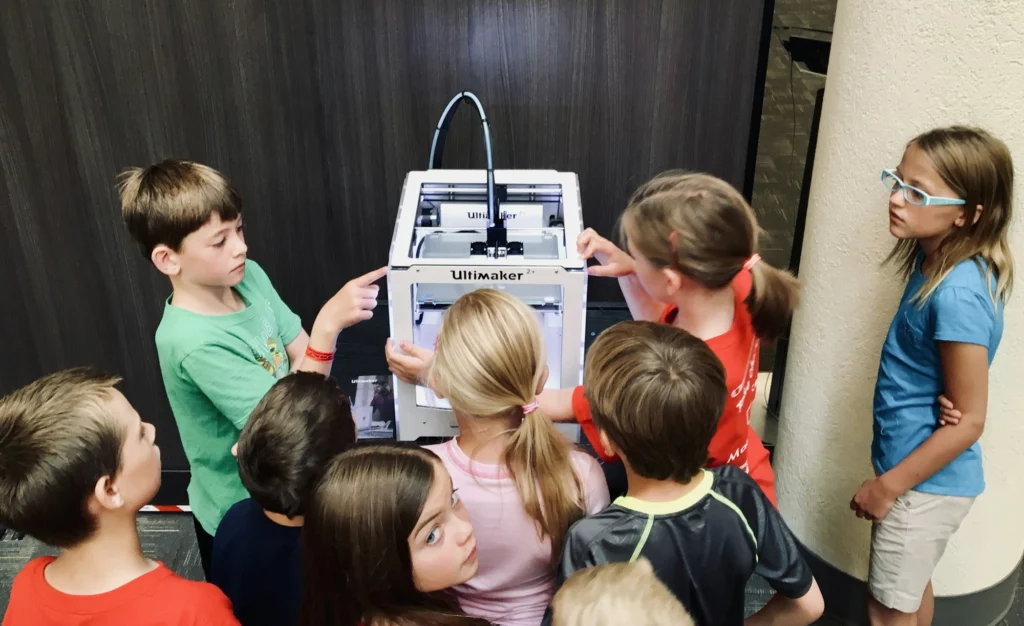 Students gathered around a 3D printer in a classroom